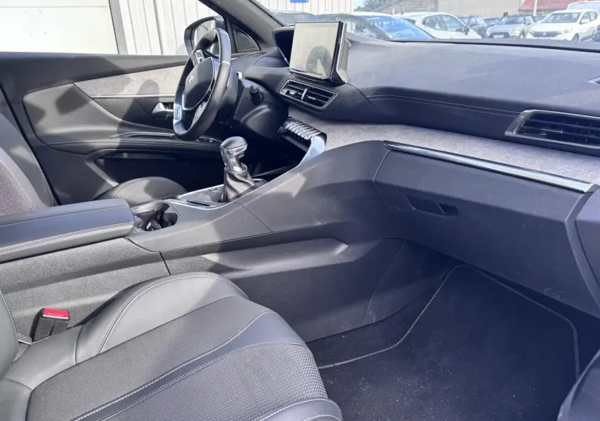 Vue intérieure côté conducteur du Peugeot 5008 blanc 2022, mettant en valeur la console centrale et le levier de vitesse manuel.