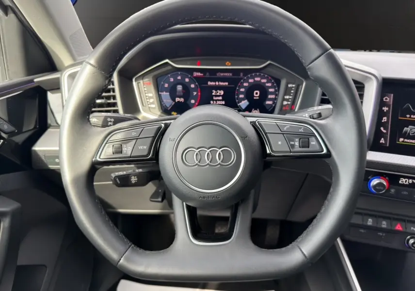 Vue rapprochée du volant cuir multifonction noir de l'Audi A1 Sportback 2025 avec tableau de bord numérique.