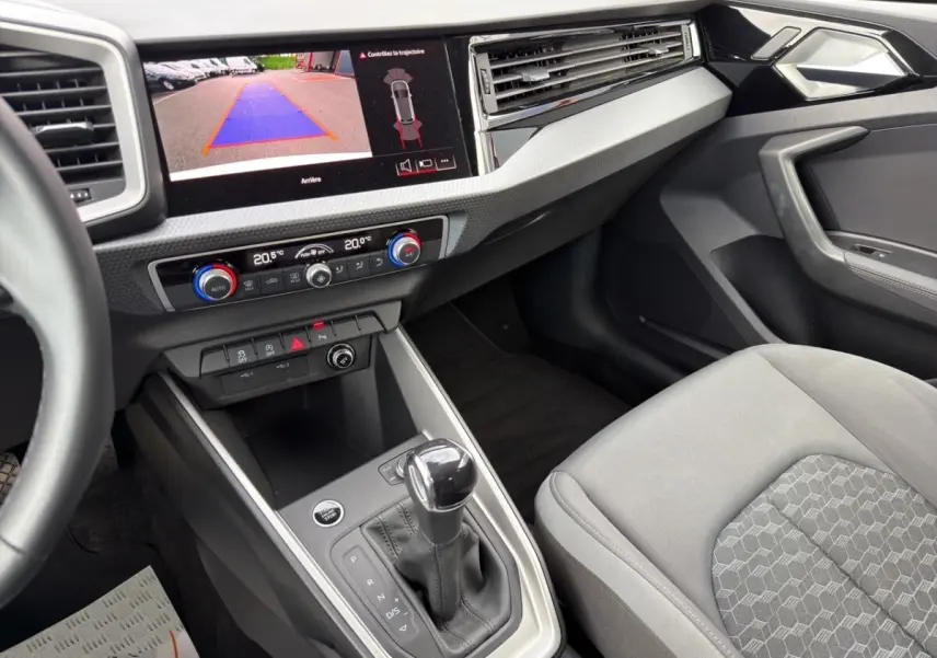 Vue intérieure côté passager de l'Audi A1 Sportback 2025 avec écran caméra de recul et levier de boîte automatique.