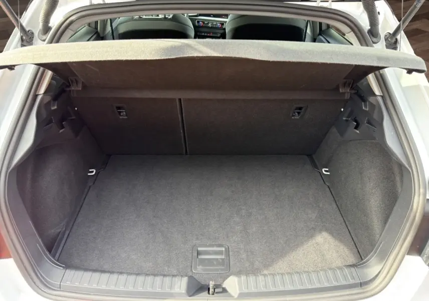 Coffre ouvert vu de l'arrière d'une Audi A1 Sportback blanche, montrant l'espace de chargement vide et la plage arrière.