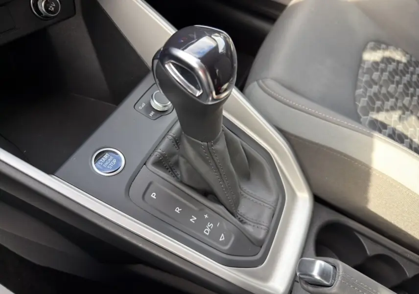 Gros plan sur la console centrale de l'Audi A1 Sportback blanche, mettant en valeur le levier de vitesse automatique et le bouton Start/Stop.