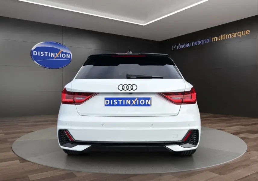 Vue arrière d'une Audi A1 Sportback blanche 2025 avec feux LED et caméra de recul en showroom.