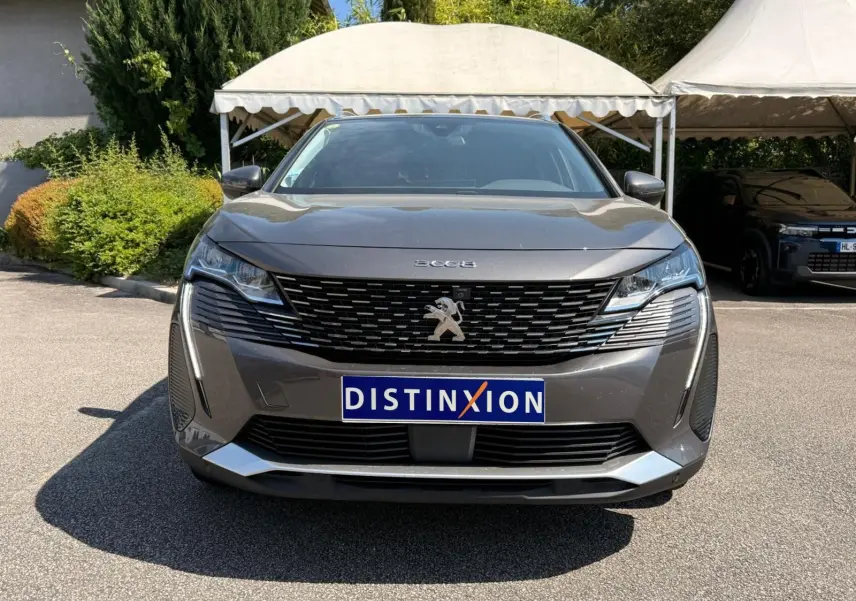Vue frontale d’un Peugeot 3008 gris platinium 2021 avec calandre noire et logo lion central bien visible.