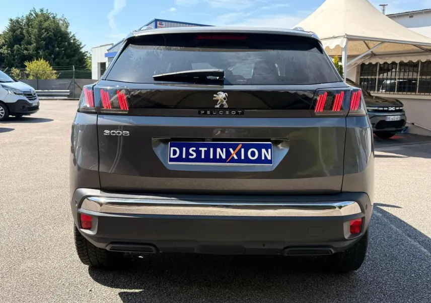 Vue arrière d’un Peugeot 3008 gris platinium 2021 avec feux arrière à griffes rouges et bandeau noir brillant.