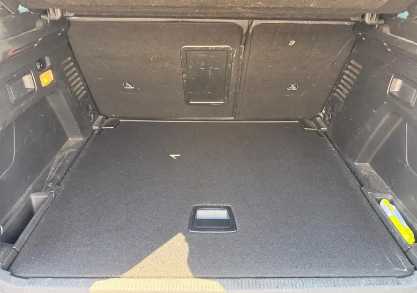 Coffre ouvert du Peugeot 3008 gris platinium, vue intérieure montrant le plancher plat et les rangements latéraux.