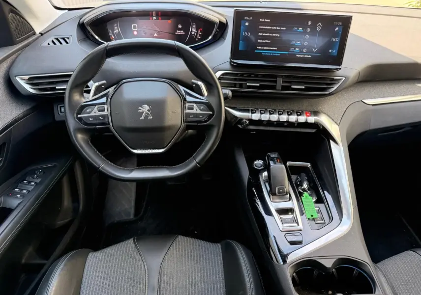Vue intérieure du poste de conduite du Peugeot 3008 gris platinium, avec volant compact, écran tactile et console centrale moderne.