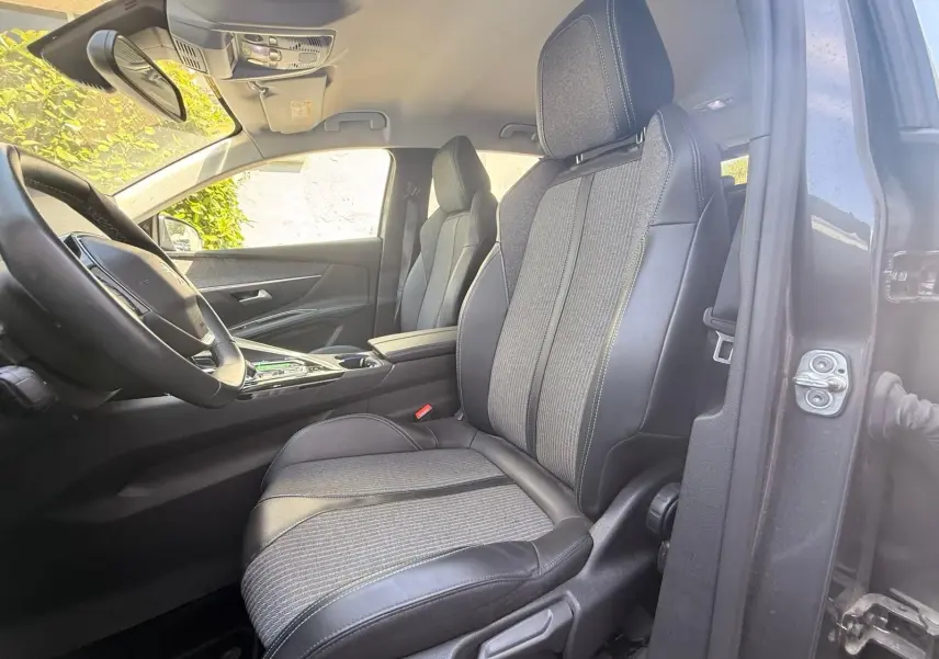 Vue intérieure côté conducteur du Peugeot 3008 2021, montrant les sièges en tissu et cuir noir avec surpiqûres contrastées.