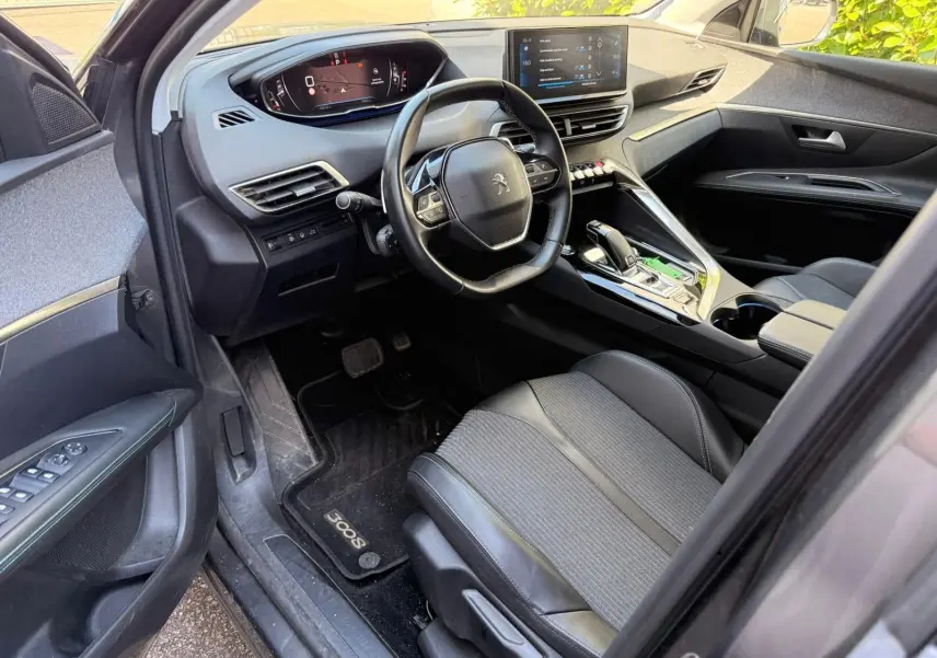 Vue intérieure côté conducteur du Peugeot 3008 gris platinium, mettant en valeur le tableau de bord numérique et la console centrale moderne.
