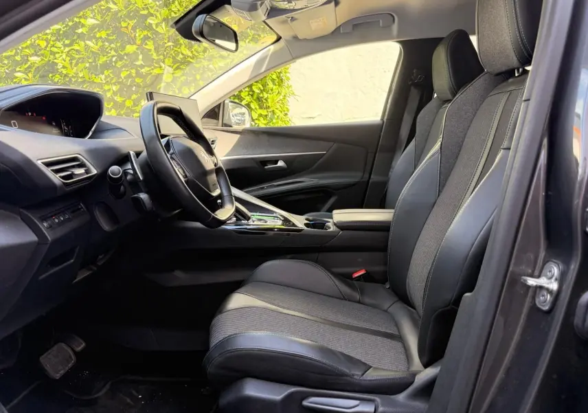 Vue intérieure côté conducteur du Peugeot 3008 gris platinium, mettant en valeur les sièges mixtes tissu et cuir et le tableau de bord moderne.