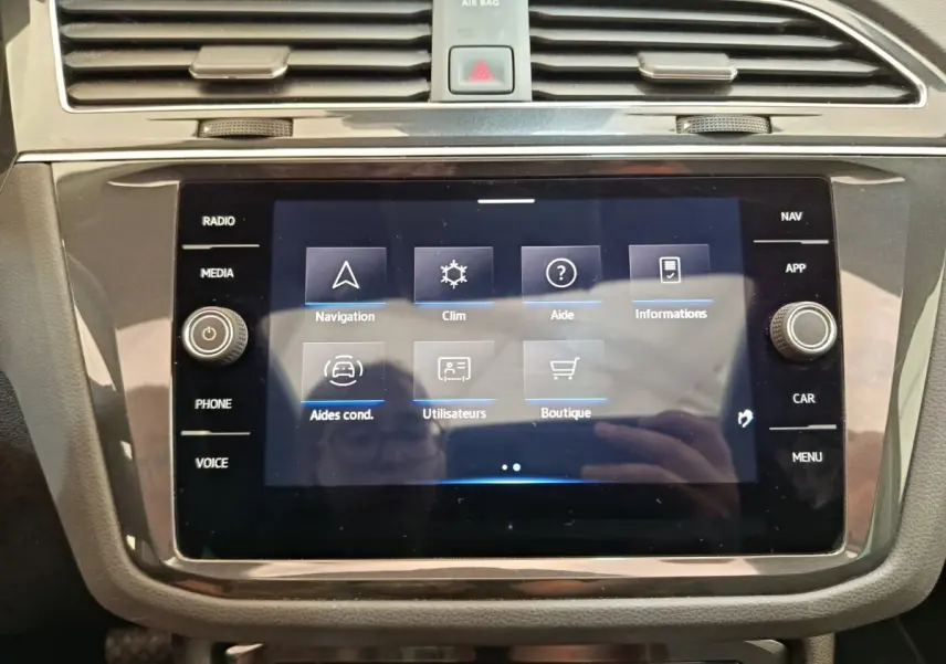 Écran tactile central du tableau de bord du Volkswagen Tiguan noir, affichant le menu de navigation et climatisation.