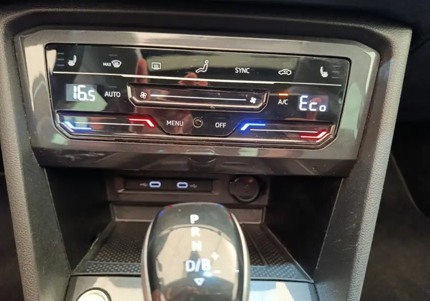Gros plan sur la console centrale noire du Volkswagen Tiguan 1.4 eHybrid avec commandes climatisation digitale et levier de boîte auto.