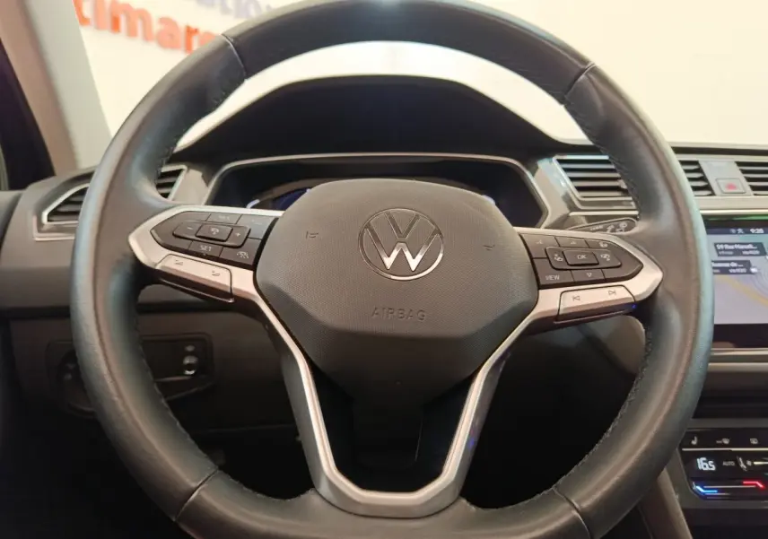 Gros plan sur le volant cuir multifonctions du Volkswagen Tiguan 1.4 eHybrid noir, avec commandes intégrées.
