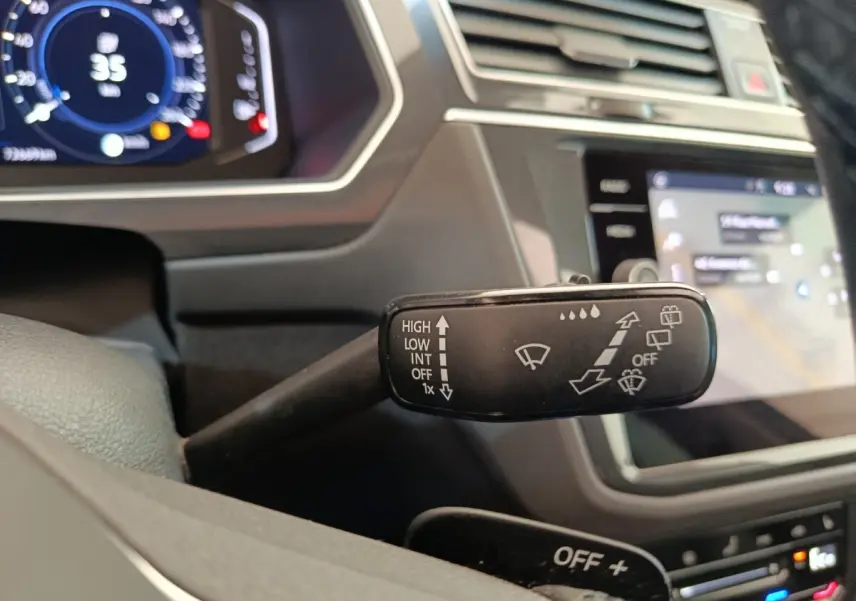 Gros plan sur la commande des essuie-glaces à gauche du volant dans l’habitacle noir du Volkswagen Tiguan 2022.