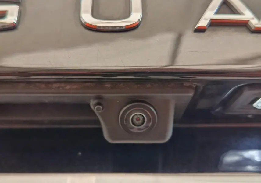 Gros plan sur la caméra de recul intégrée sous le coffre noir d’un Volkswagen Tiguan hybride rechargeable.