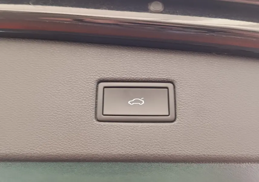 Bouton d'ouverture électrique du coffre sur la garniture intérieure d'un Volkswagen Tiguan noir, vue rapprochée.