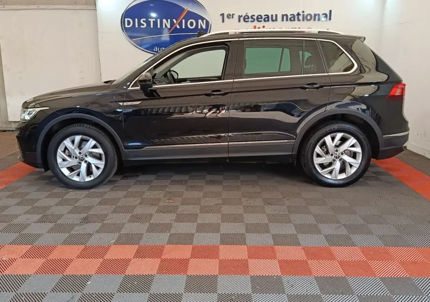 Vue de profil côté gauche d'un Volkswagen Tiguan noir 1.4 eHybrid 245 DSG6 Elegance Exclusive dans un showroom.