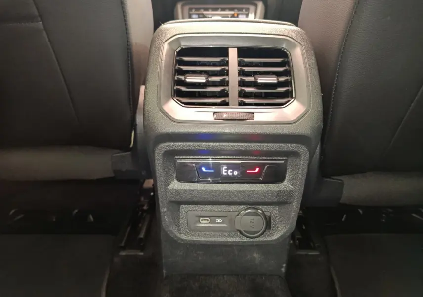 Vue rapprochée de la console arrière noire du Volkswagen Tiguan 2022 avec commandes climatisation et prises USB et 12V.