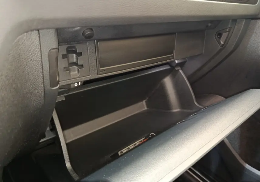 Vue intérieure sur la boîte à gants ouverte du Volkswagen Tiguan noir, version hybride rechargeable 2022.