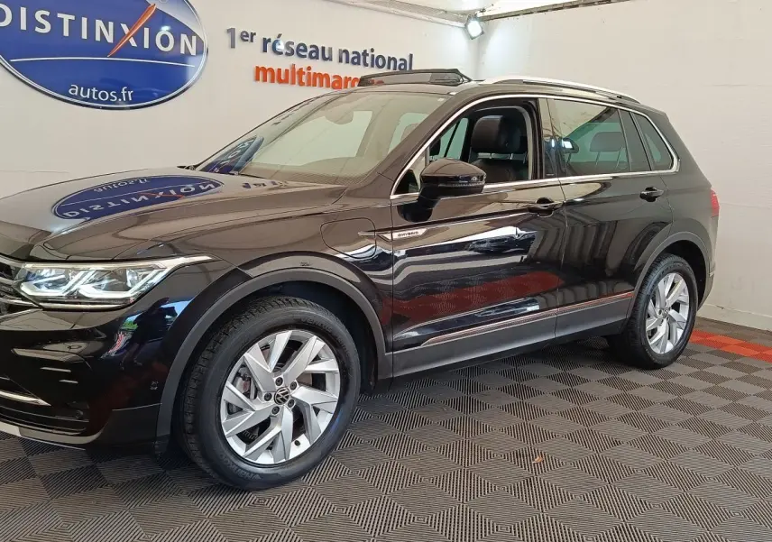 Volkswagen Tiguan 1.4 eHybrid noir en vue 3/4 avant droit, avec jantes alliage et badge hybride visible sur aile avant.