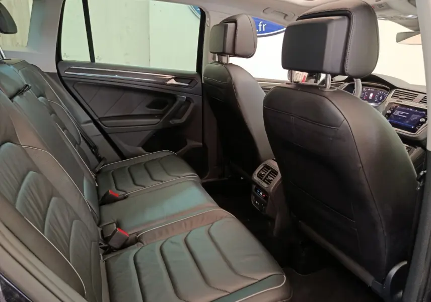Vue intérieure côté droit montrant la banquette arrière en cuir noir et les sièges avant du Volkswagen Tiguan 1.4 eHybrid 2022.