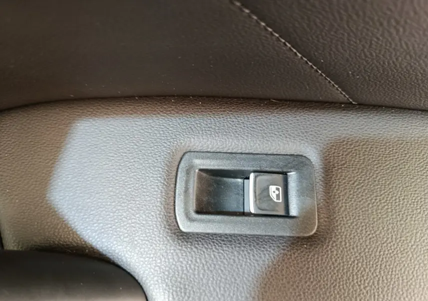 Bouton de commande de lève-vitre arrière droit sur panneau intérieur noir d'un Volkswagen Tiguan 2022.