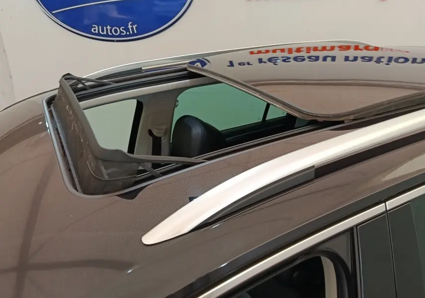 Vue rapprochée du toit ouvrant panoramique ouvert sur un Volkswagen Tiguan noir, avec rails de toit chromés visibles.