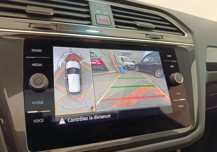 Écran tactile central montrant la caméra de recul et l’aide au stationnement du Volkswagen Tiguan noir.