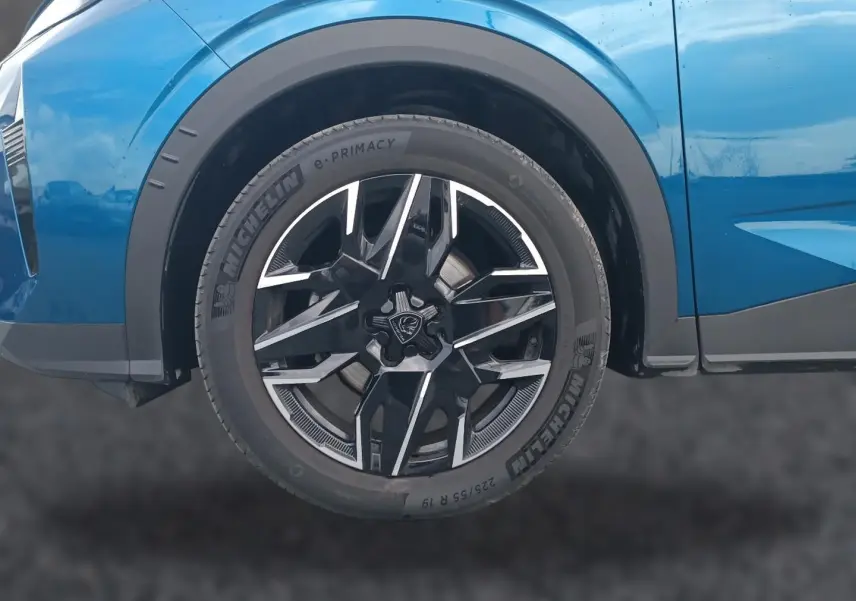 Gros plan sur la roue avant droite d’un Peugeot 3008 bleu avec jante alliage noire et argentée.
