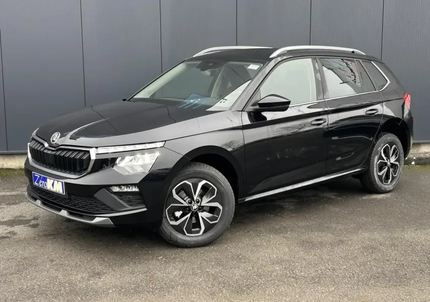 Vue 3/4 avant droite d'un Skoda Kamiq noir Magic avec jantes alliage et baguettes chromées sur fond urbain.