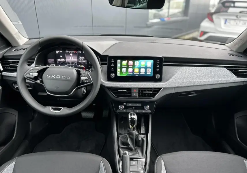 Vue intérieure avant du Skoda Kamiq noir Magic 2025, tableau de bord avec écran tactile Apple CarPlay et volant multifonctions.