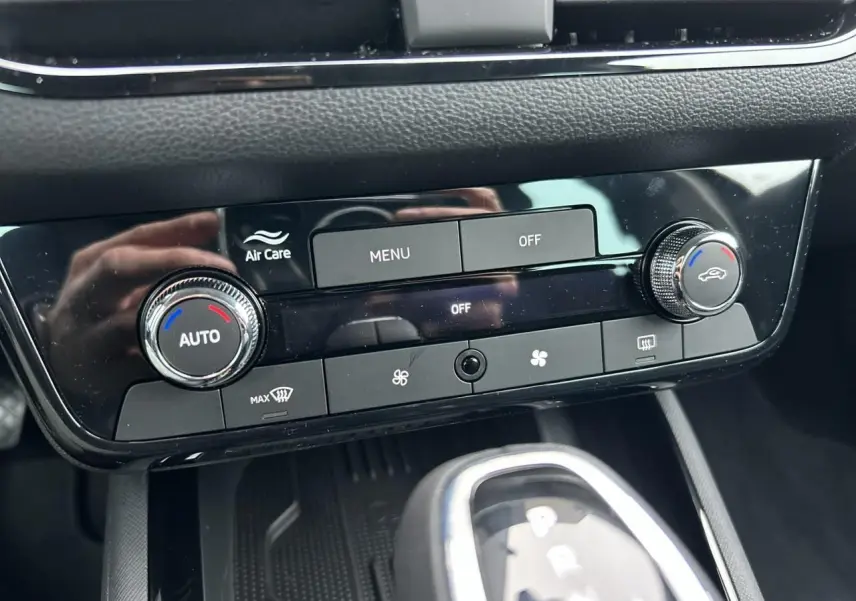Gros plan sur la console centrale noire du Skoda Kamiq 2025, avec commandes climatisation automatique et levier de boîte auto.
