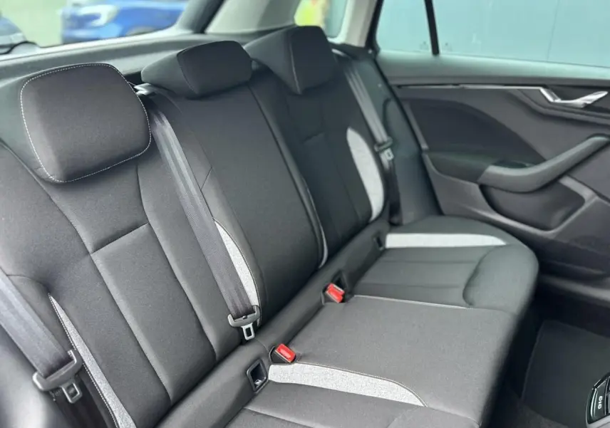 Vue intérieure du siège arrière droit d'une Skoda Kamiq noir Magic, avec ceintures et garnitures grises contrastantes.