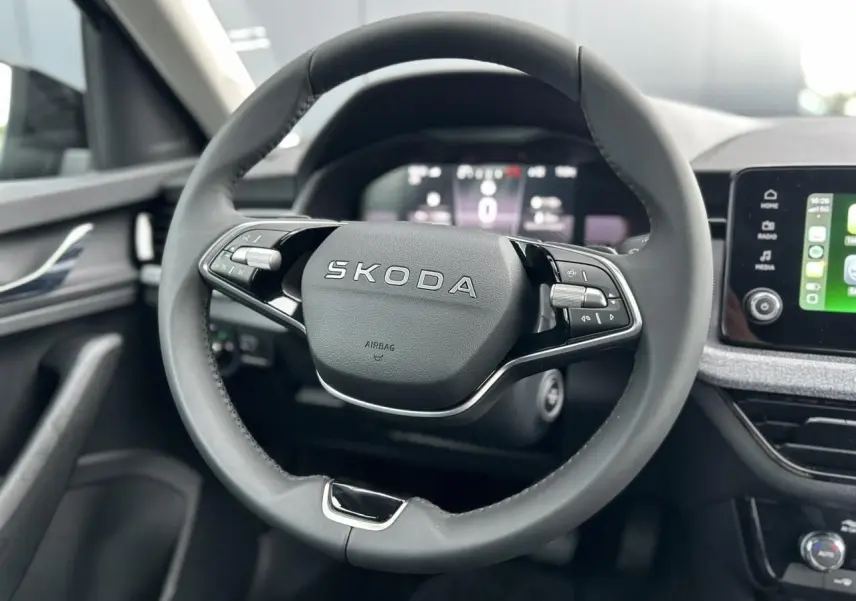 Vue rapprochée du volant cuir noir multifonctions SKODA KAMIQ 2025 avec tableau de bord digital et écran tactile Apple CarPlay.