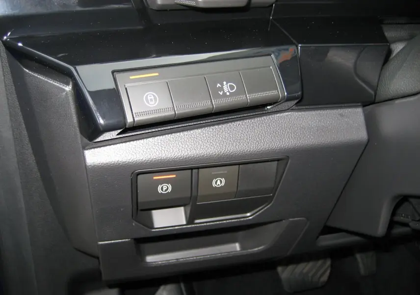 Gros plan sur les commandes de réglage des feux et frein de stationnement du Renault Austral 2025, intérieur noir.
