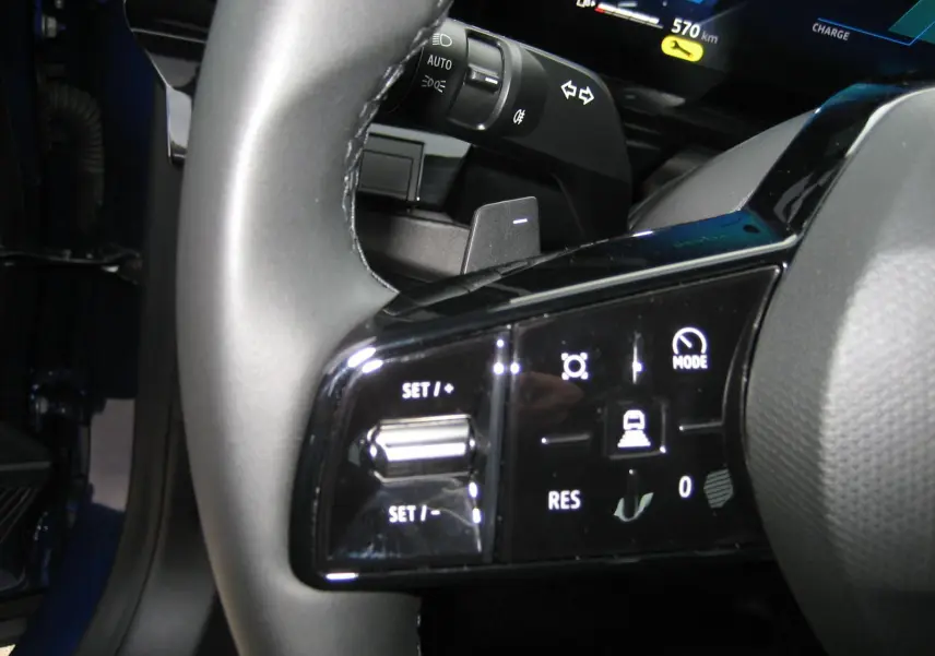 Gros plan sur les commandes au volant du Renault Austral bleu Iron, avec affichage digital et boutons de régulateur de vitesse.