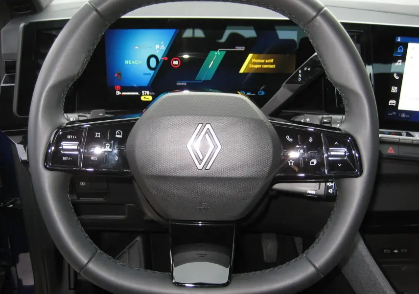 Vue rapprochée du volant multifonctions noir du Renault Austral 2025 avec tableau de bord numérique allumé.