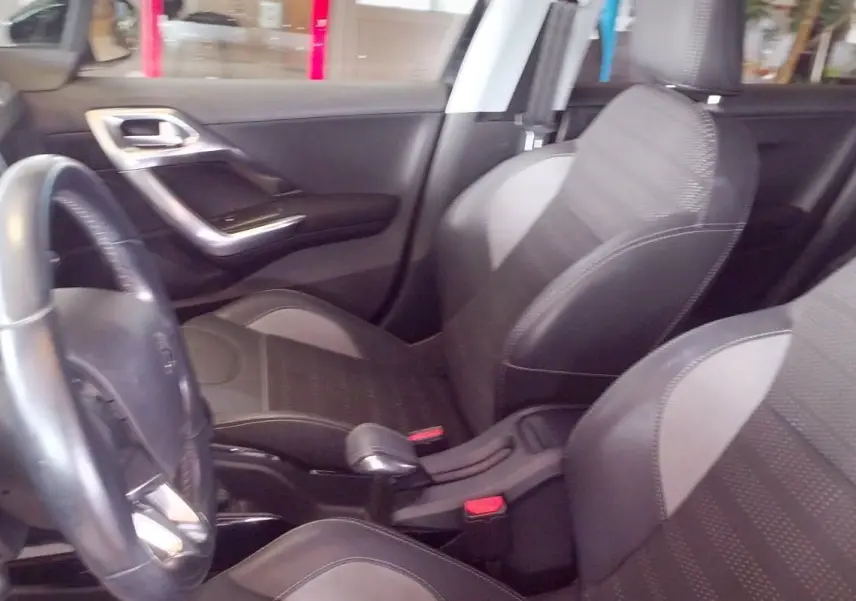 Intérieur noir de la Peugeot 208 2023, vue côté conducteur montrant volant, sièges et console centrale.