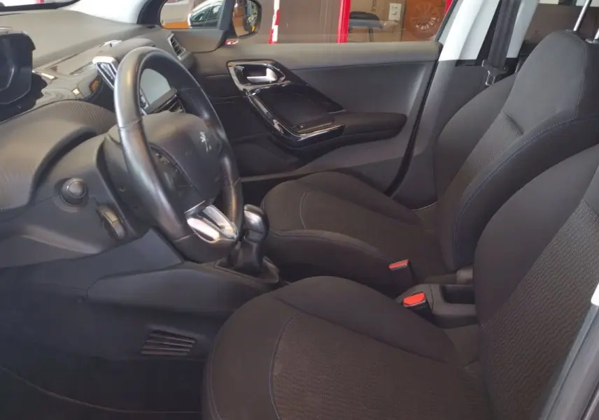 Intérieur avant gauche de la Peugeot 208 1.6l HDi 75 ch 2023 avec sièges noirs et volant cuir.