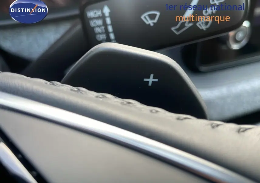 Gros plan sur la palette de changement de vitesse droite et partie du volant en cuir noir d'un Skoda Kamiq gris argent.