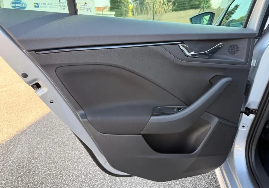 Vue intérieure de la porte arrière gauche d’un Skoda Kamiq gris argent, avec garniture noire et poignée chromée.