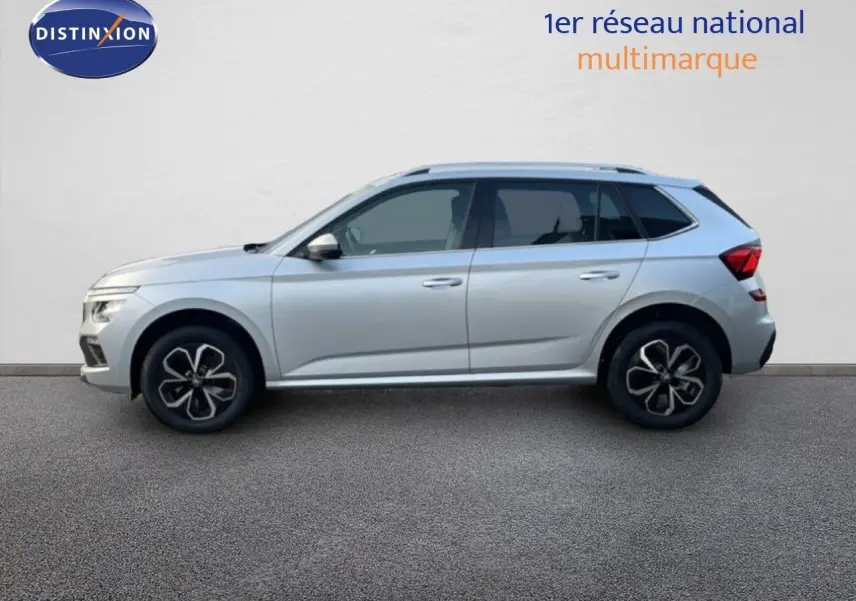 Vue de profil côté gauche d'un Skoda Kamiq gris argent métallisé avec jantes noires et toit ouvrant.