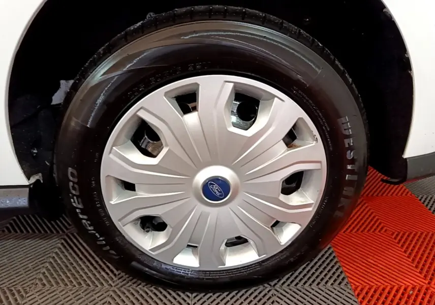 Gros plan sur la roue avant droite du Ford Transit Fourgon blanc, mettant en valeur la jante avec enjoliveur argenté.