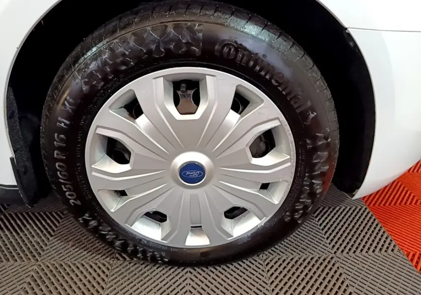 Gros plan sur la roue avant droite d’un Ford Transit Fourgon blanc avec enjoliveur argenté et pneu Continental.