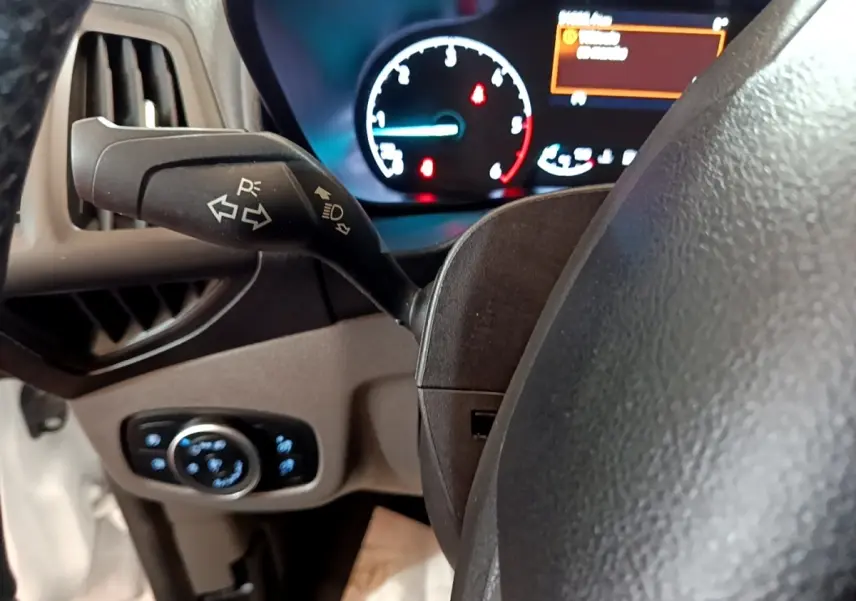 Gros plan sur le commodo gauche et le tableau de bord éclairé du Ford Transit Fourgon blanc, version 2022.