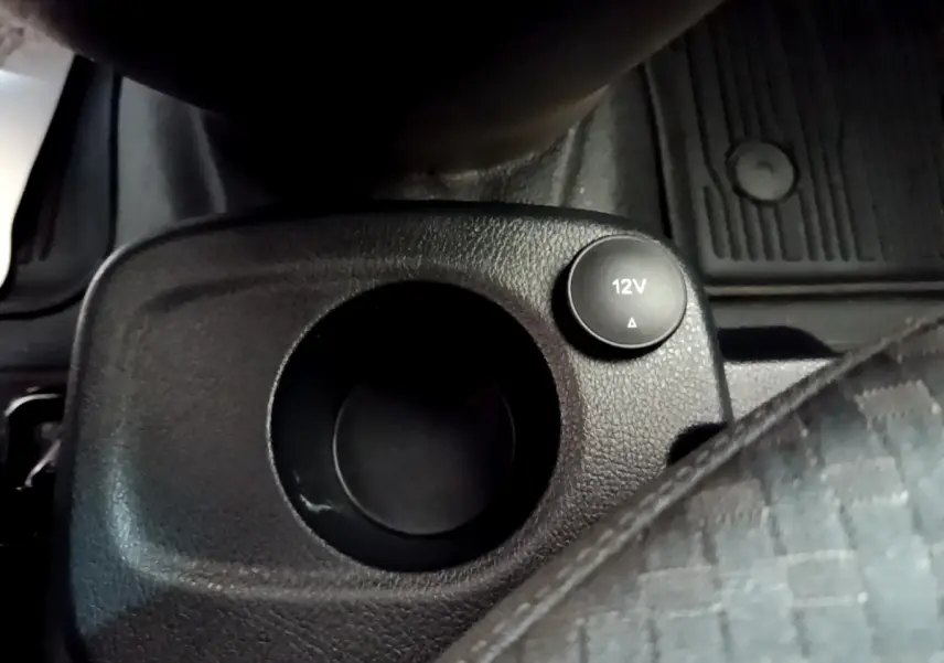 Gros plan sur la prise 12V et porte-gobelet noir dans l’habitacle du Ford Transit Fourgon blanc, côté conducteur.