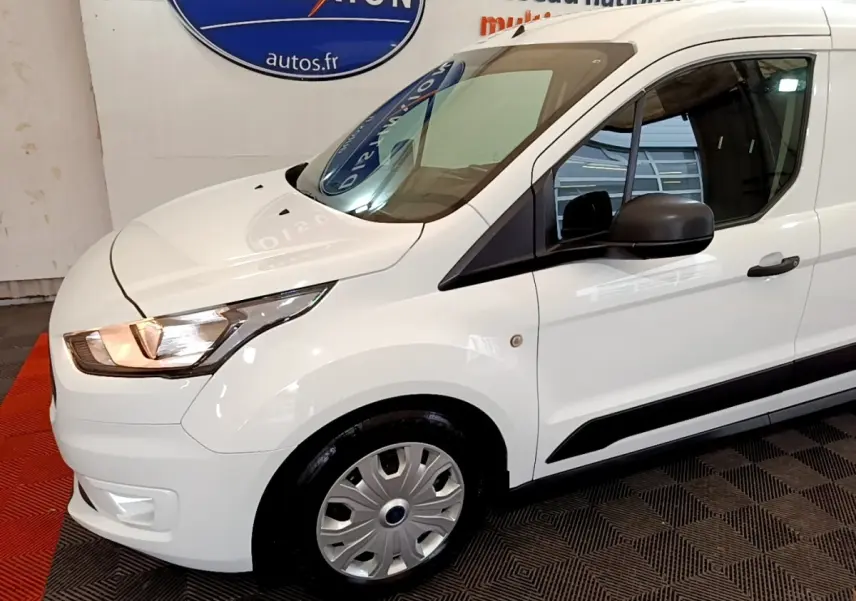 Vue 3/4 avant droit d’un Ford Transit Fourgon blanc avec phares allumés et jantes acier.