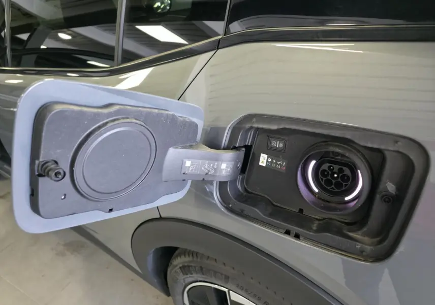 Prise de recharge ouverte côté gauche sur Peugeot 408 gris métallisé, avec jante alliage 19 pouces visible.