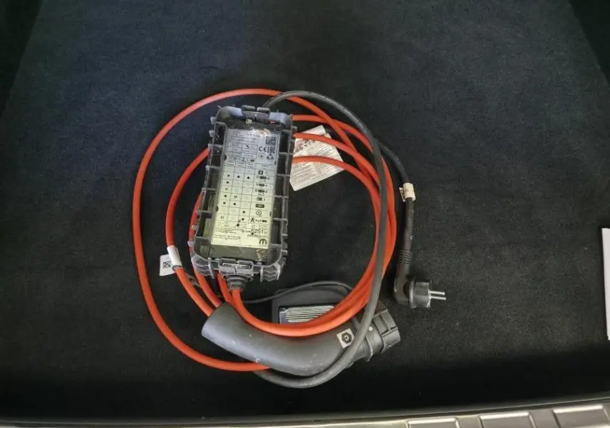 Câble de recharge hybride rouge et noir posé dans le coffre d'une Peugeot 408 gris Selenium.