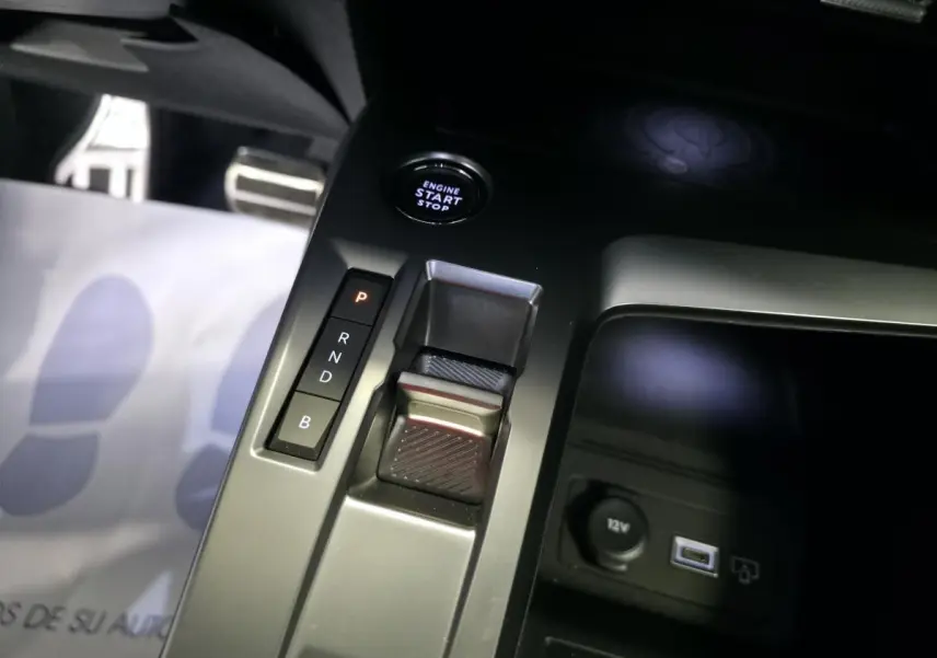 Gros plan sur la console centrale noire de la Peugeot 408 hybride, montrant la commande de boîte auto et bouton start/stop.