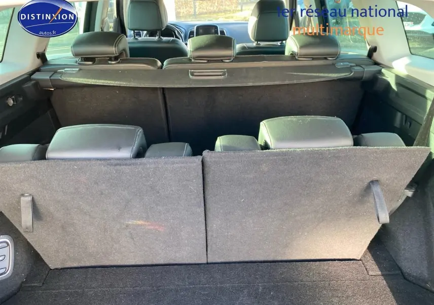 Vue arrière du coffre du Renault Grand Scenic IV bleu, sièges arrière partiellement rabattus et cache-bagages en place.